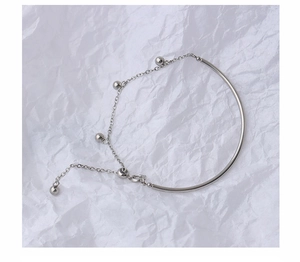 Detailed shot of silver tassel bracelet with polished metal beads on textured paper