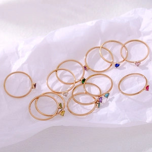 Detail of 12 colorful heart-shaped birthstone rings with polished gold-plated bands