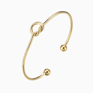 Minimalist 14K gold plated stainless steel knot bangle with ball ends on white background