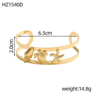Detailed view of gold C-shaped sea charm bracelet with shell, turtle, and starfish charms