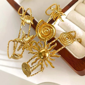 Golden ocean theme cuff bracelets with starfish and shell charms on a velvet box