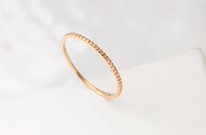 Macro view of minimalist rose gold ring with vertical gear-like grooved texture detail