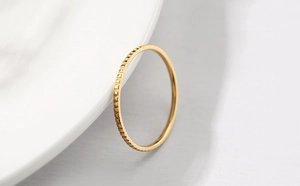 Detailed macro view of the textured vertical grooves on a minimalist golden band ring