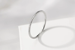 Macro detail of silver stainless steel ring featuring relief square textured pattern