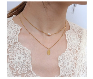 Detalle de un collar doble de oro con una perla y un colgante grabado Hand Made