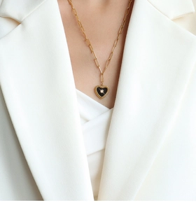 Detail of a 18K gold plated heart pendant with black enamel on a paperclip chain necklace