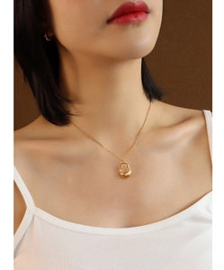 Primer plano de collar con colgante hueco dorado en una modelo femenina