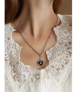 Macro shot of 18K gold plated paperclip chain with black heart pendant on a lace collar