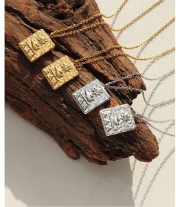 Detailed view of square sunburst pendants in gold and silver with hammer-textured finish