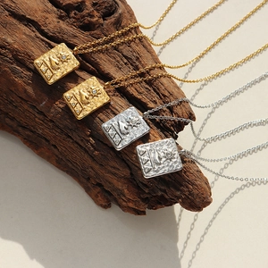 Retro stainless steel sun pendant necklaces in gold and silver on a rustic wood base