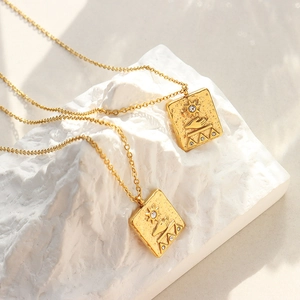 Vintage gold sun and palm square pendant necklace with hammered texture on white stand