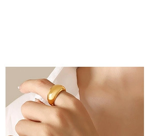 Gros plan d'une bague dorée épaisse minimaliste au fini poli portée à l'index