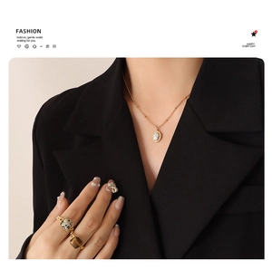 Detailaufnahme von Vintage Katzenaugen-Halskette und Goldring-Set auf schwarzer Kleidung