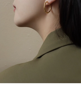 Golden bamboo-style hoop earrings on a model, elegant gold-plated titanium steel design