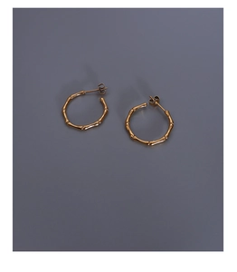 Close-up of golden bamboo-shaped earrings with metallic luster on dark background