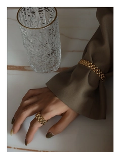 Detail of gold watchband link bracelet and matching ring set on a female model