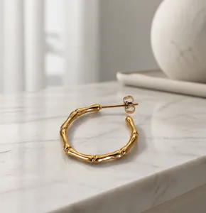 Close-up of golden bamboo joint hoop earrings made of titanium steel with mirror finish