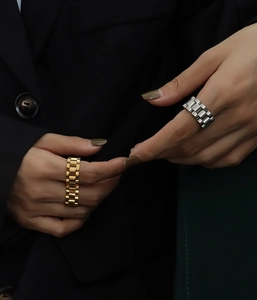 Detail of gold and silver watch-band style stainless steel rings with oyster links