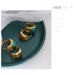 Detail von goldenen Edelstahlringen mit grünem Malachit und braunem Tigerauge im Vintage-Stil