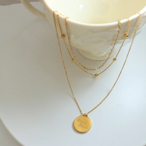 Three-layer gold layered necklace with circular coin pendant and Good Luck engraving