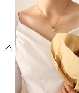 Primer plano del collar con colgante de grulla de origami de oro en una modelo
