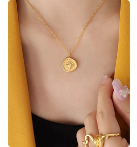 Close-up of a gold compass pendant necklace featuring an eight-pointed star and NSEW engraving