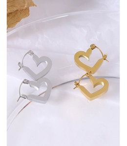 Detailed view of heart-shaped hollow earrings in polished gold and silver steel finish