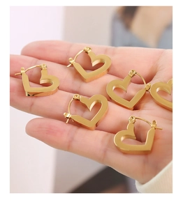 Close-up of three pairs of hollow heart-shaped gold hoop earrings held in hand