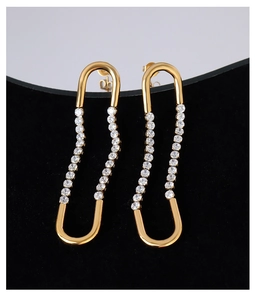 Macro detail of French gold U-shaped earrings with zircon inlay on a minimalist backdrop
