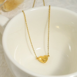 Detail of 18K gold-plated magnetic heart pendant necklace inside a white porcelain cup