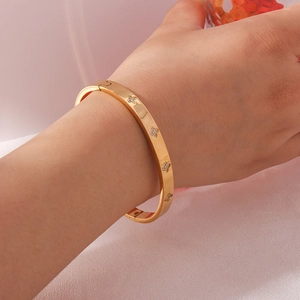 Macro detail of gold clover bangle featuring pavé-set stones and a hinged clasp design