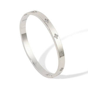 Macro shot of silver bangle with CNC inlaid sparkling clover motifs and secure buckle closure