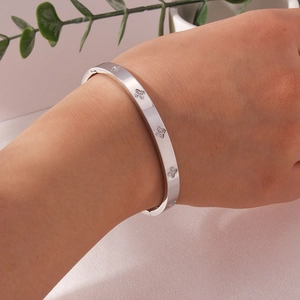 Detail of silver clover bangle with CNC set sparkling stones on female wrist