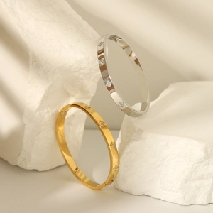 Gold and silver four-leaf clover bangles with CNC diamond settings on a white stone base