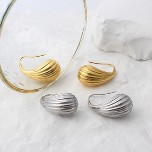 Detailed view of textured gold and silver teardrop earrings with elegant ribbed patterns