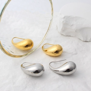 Detailed view of teardrop earrings in polished gold and silver finishes on stone