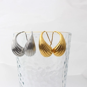 Detail showing gold and silver hollow teardrop earrings with textured stripes on glass