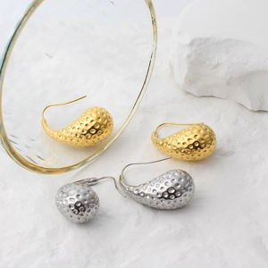 Detailed view of teardrop earrings with gold and silver hammered metal texture finish
