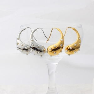 Detail of 18K hollow teardrop earrings with pearls on a transparent glass edge
