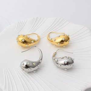 Detailed view of teardrop hollow earrings in gold and silver finish with small pearls
