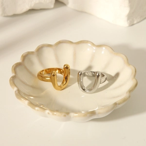 Detailed close-up of gold and silver U-shaped chunky rings in a ceramic jewelry dish
