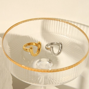 Polished 18k gold and silver stainless steel U-shaped sculptural rings in a glass