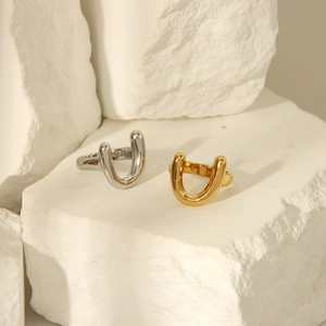 Close-up of minimalist U-shaped 18k gold and silver rings on white textured stone