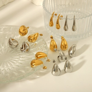 Polished gold and silver teardrop stud earrings set in a minimalist modern aesthetic