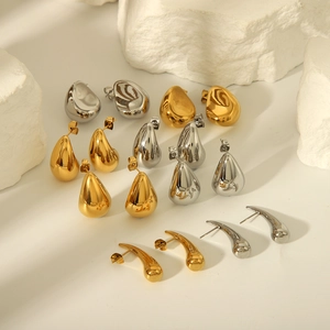 Polished 18K gold and silver chunky teardrop stud earrings set on a stone display