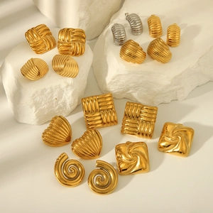 Selectie van geometrische gouden oorbellen met texturen op een witte steenachtergrond