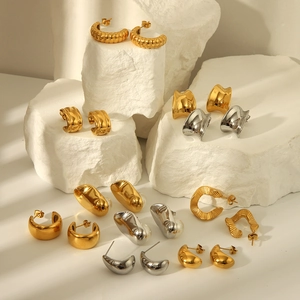 Polished 18K gold and silver geometric twisted earrings on white textured stones