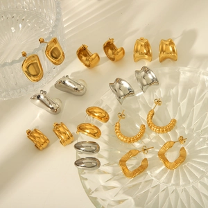 Detailed close-up of mixed 18K gold and silver geometric twisted earrings on glass tray