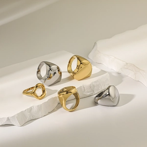 Close-up of minimalist 18K gold and silver chunky geometric rings on stone blocks