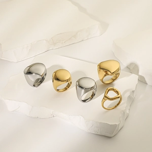 Macro shot of minimalist gold and silver polished geometric rings on white stone display